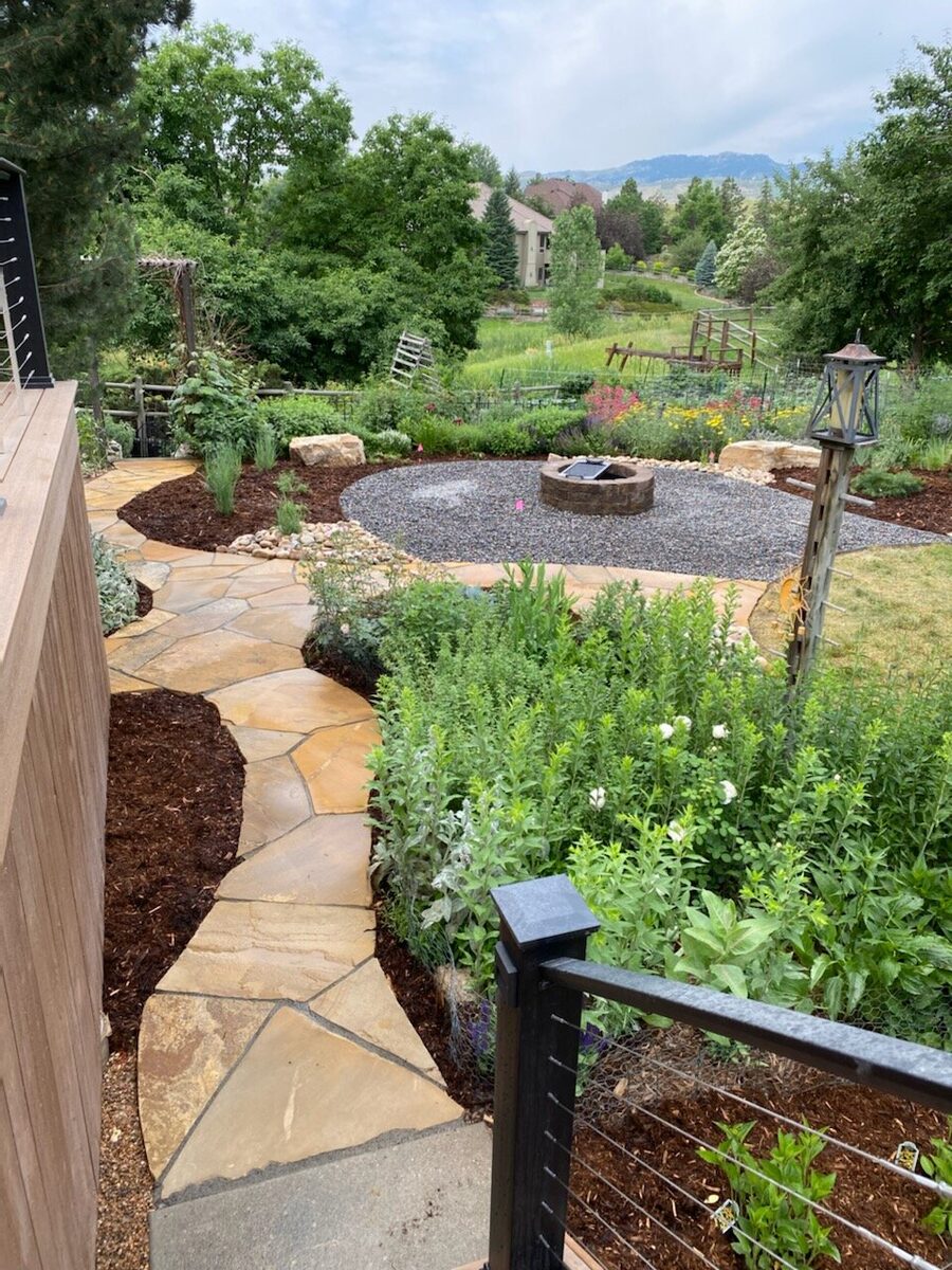 Cottage garden with a flagstone path and fire pit by Brooks Landscape
