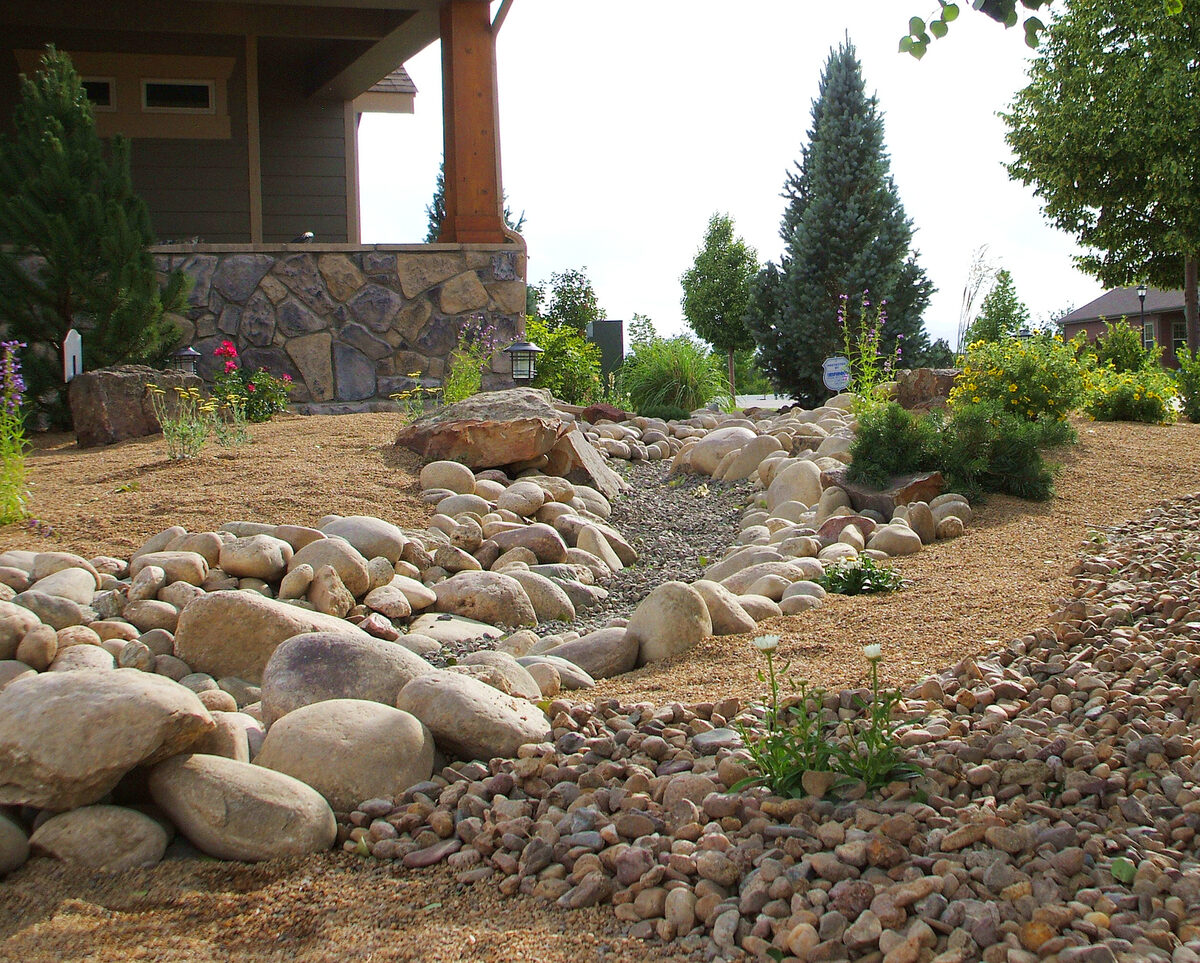 Dry creek bed with river rock for drainage by Brooks Landscape