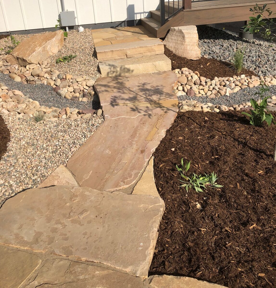 Flagstone steps bordered by river-rock beds by Brooks Landscape