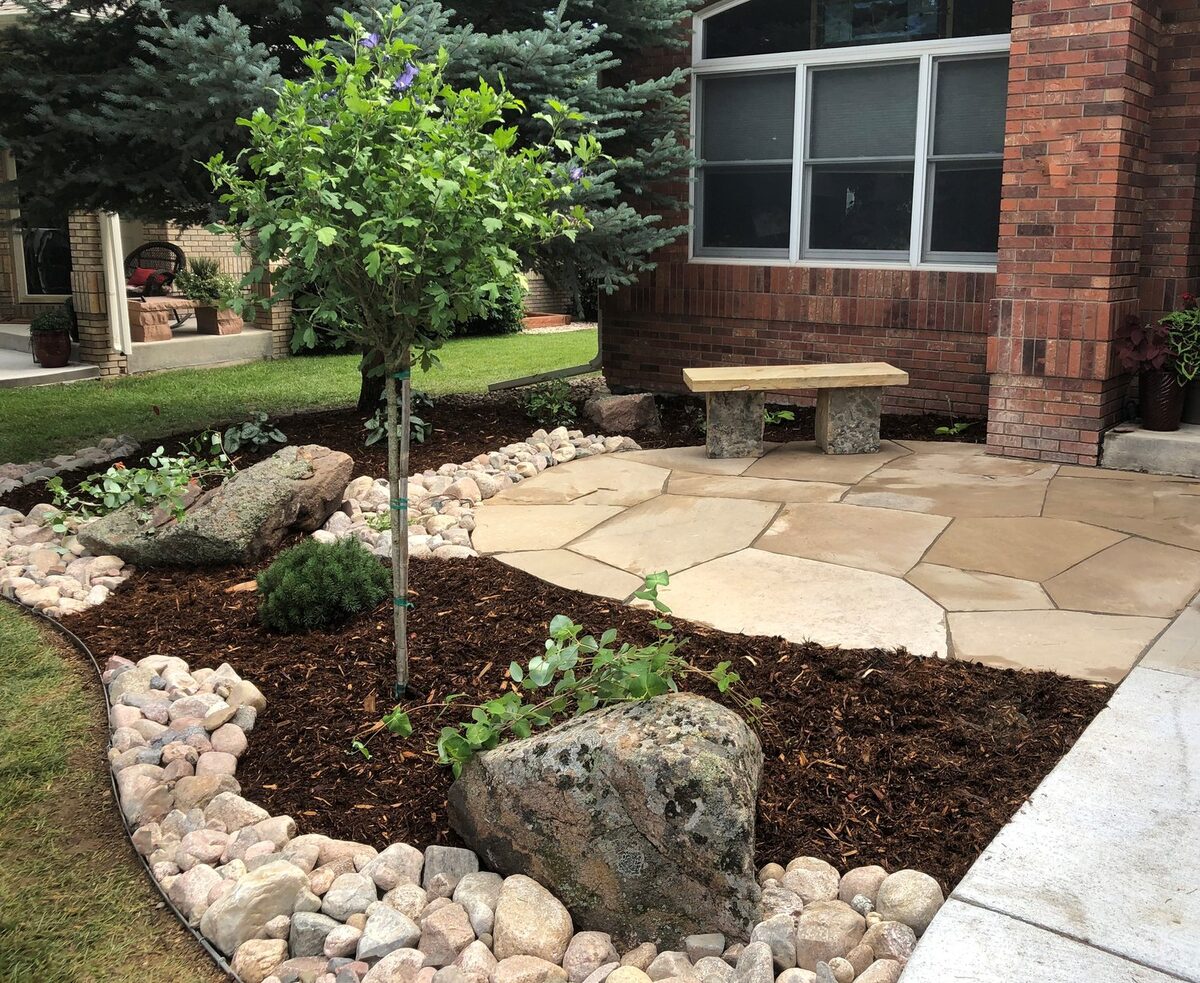 Front-entry flagstone patio with a stone bench by Brooks Landscape