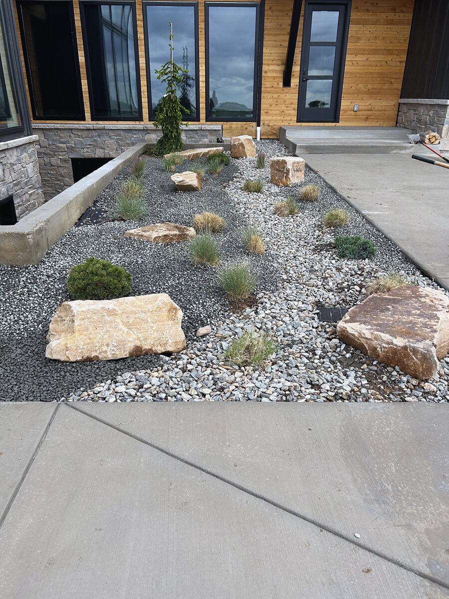 Modern xeriscape with ornamental grasses and accent boulders by Brooks Landscape