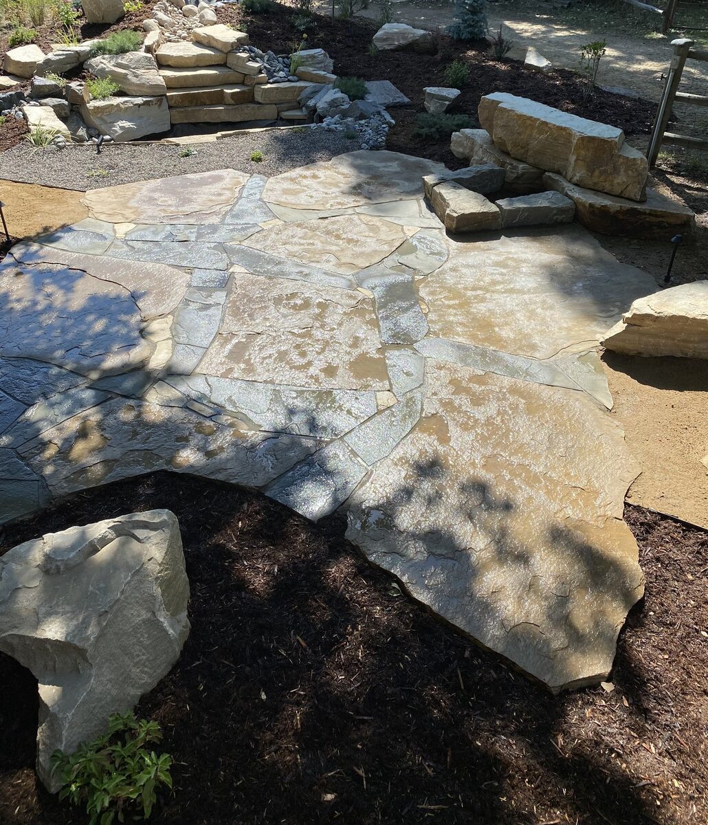 Natural flagstone patio with boulder steps by Brooks Landscape