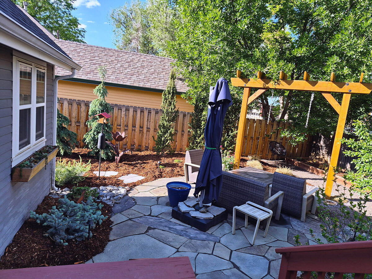 Backyard pergola shading a flagstone patio by Brooks Landscape
