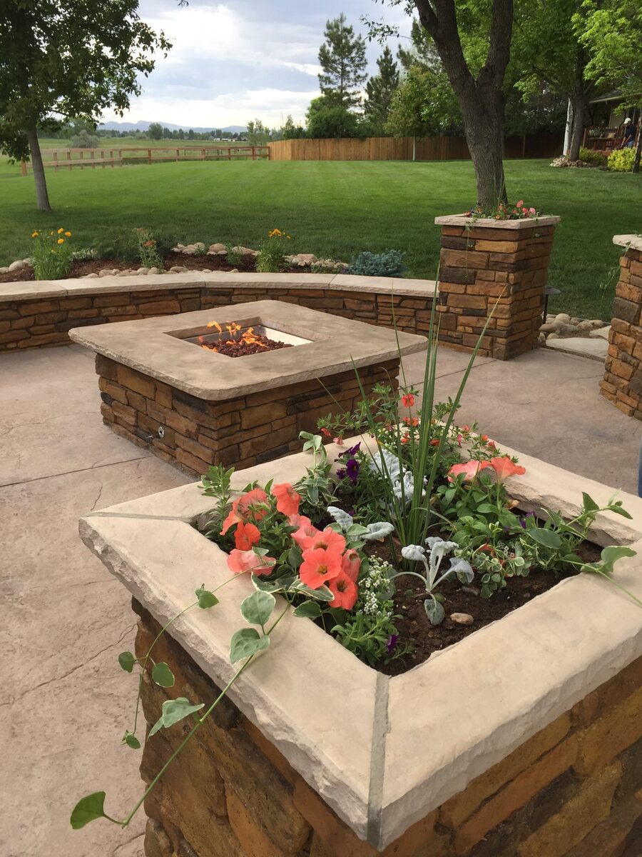 Stone gas fire pit with seat walls by Brooks Landscape
