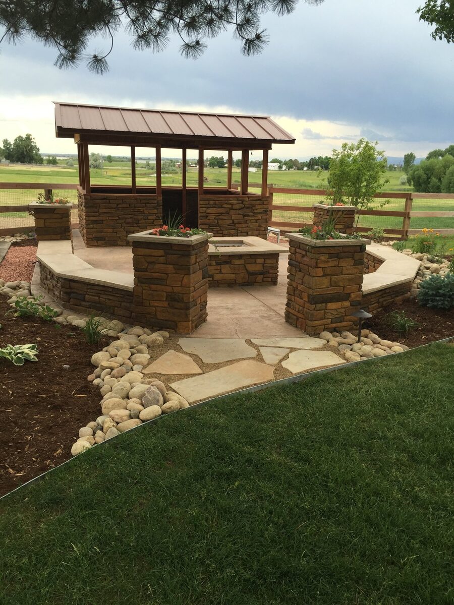 Covered stone pavilion with a fire pit built by Brooks Landscape