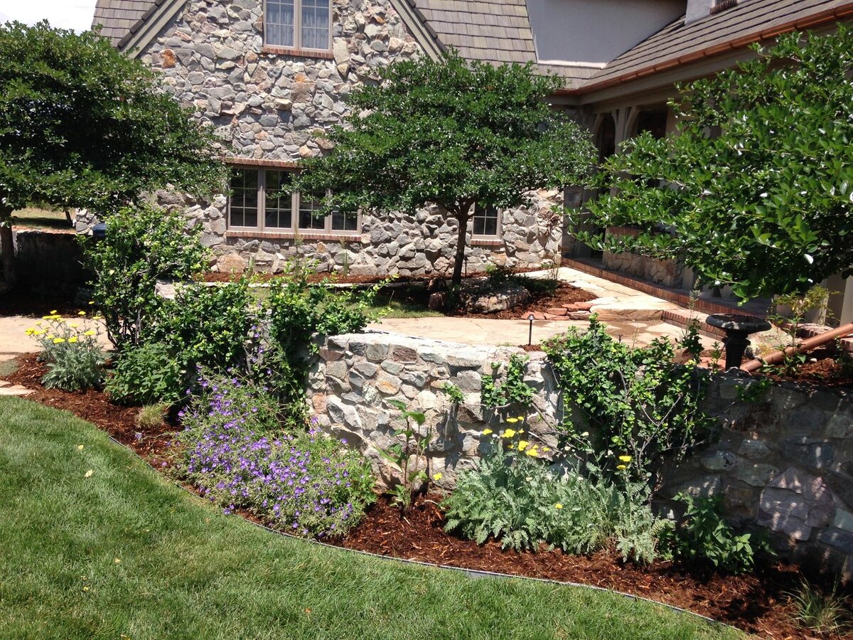 Natural stone retaining wall with cottage-style plantings by Brooks Landscape