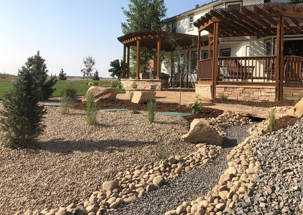 Timber pergola with stone columns and a dry creek bed by Brooks Landscape
